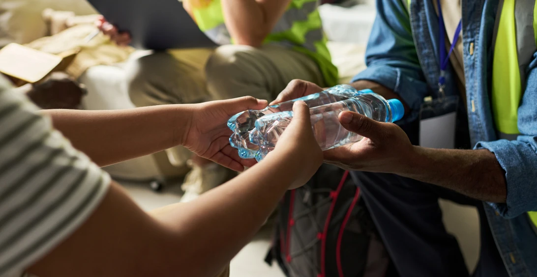 Hands exchanging a plastic water bottle.